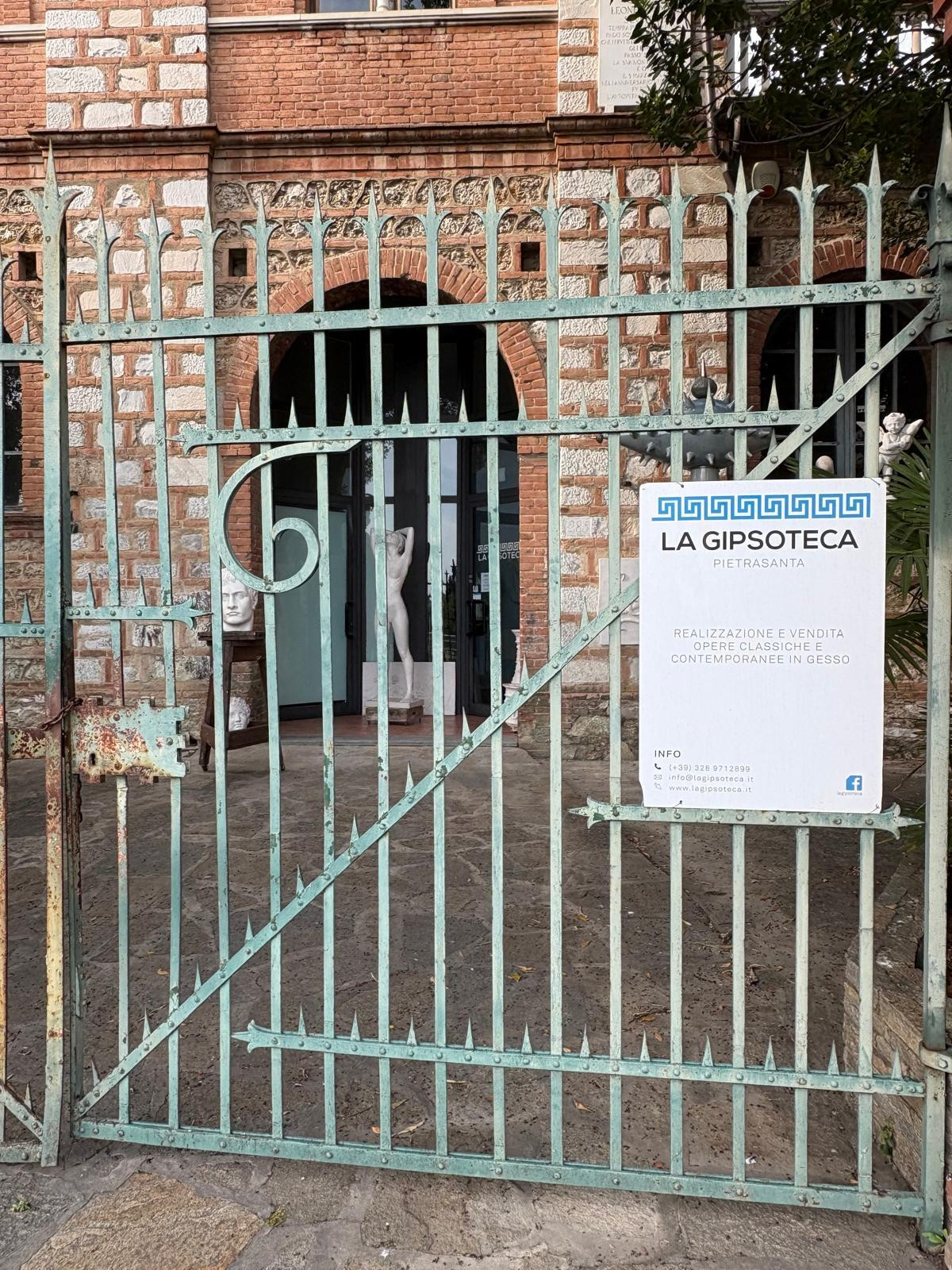 Green metal gate leading to ornate red brick building