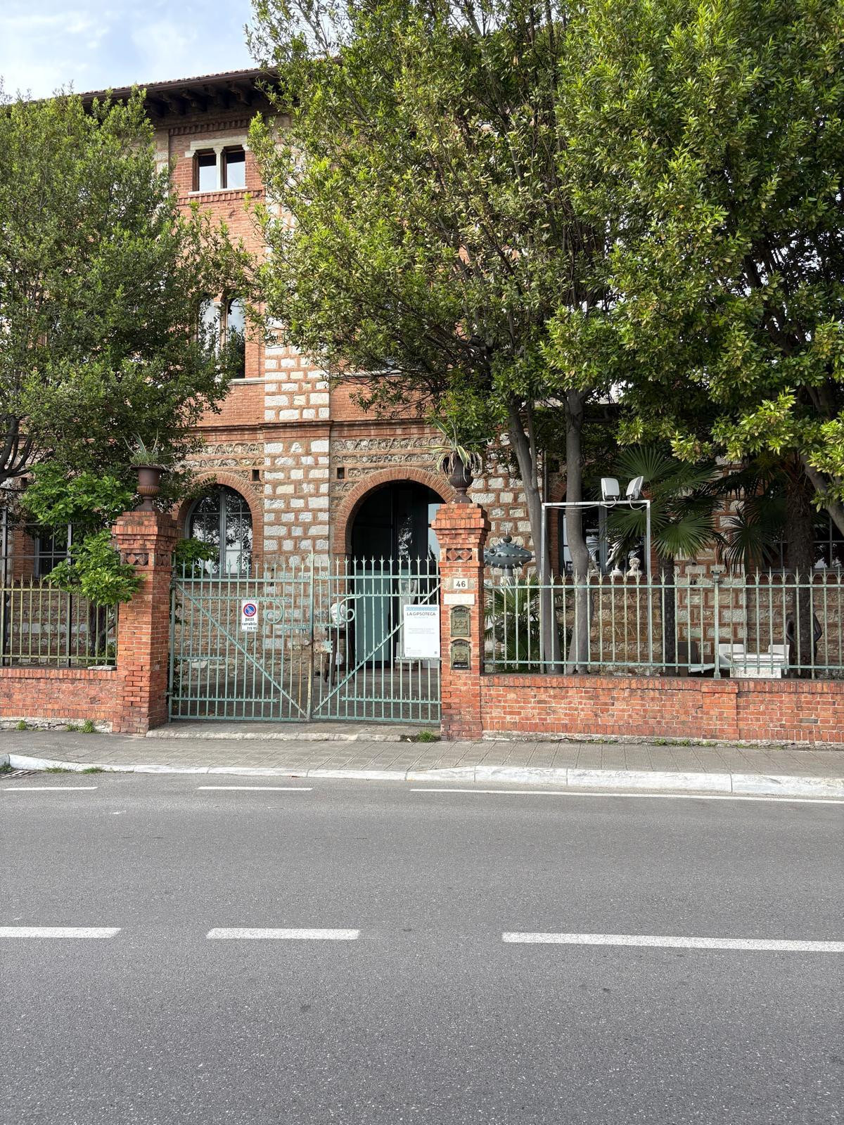red brick building with green gates and trees