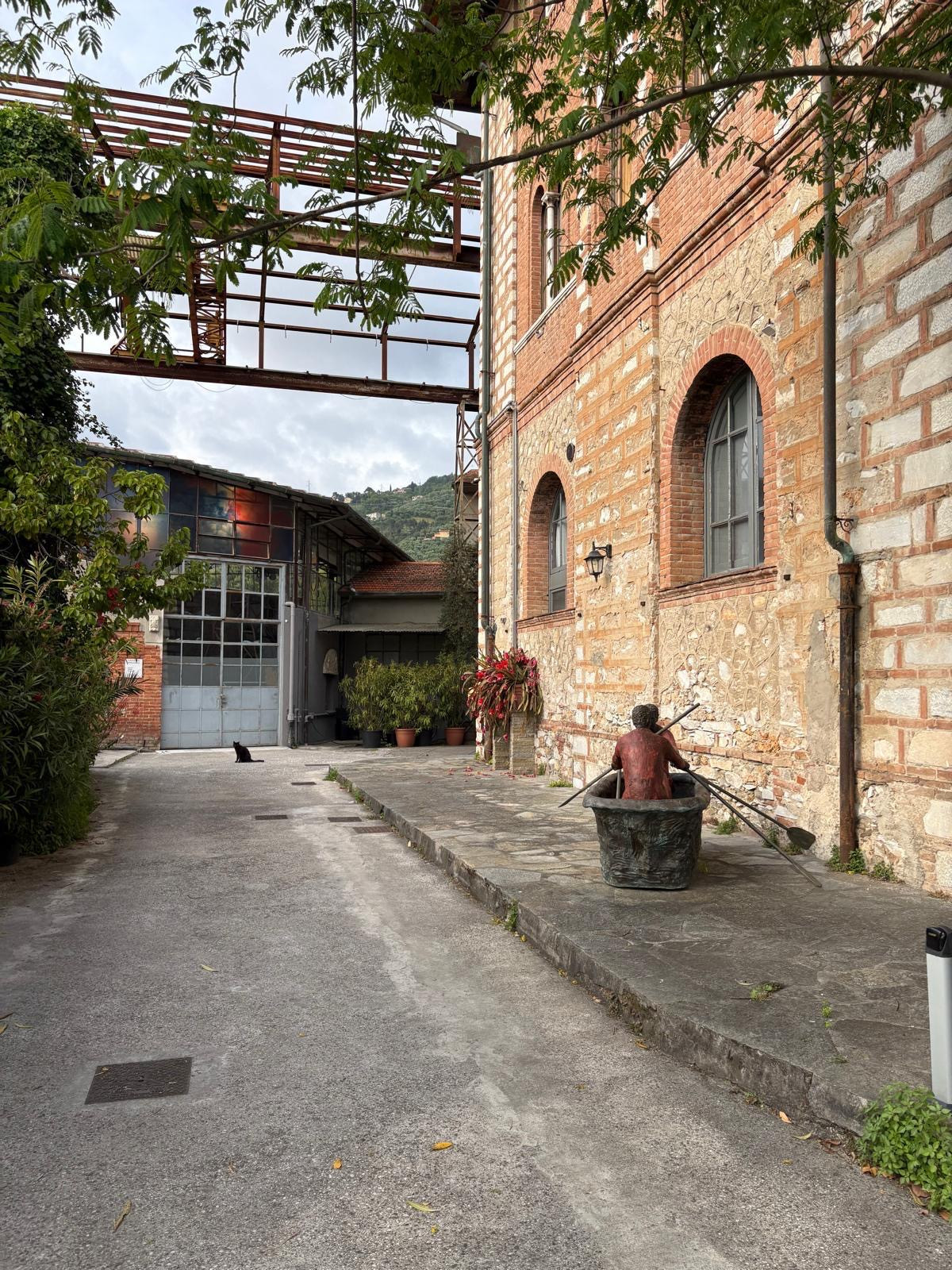 pathway leading to double doors and a black cat next to a red brick building