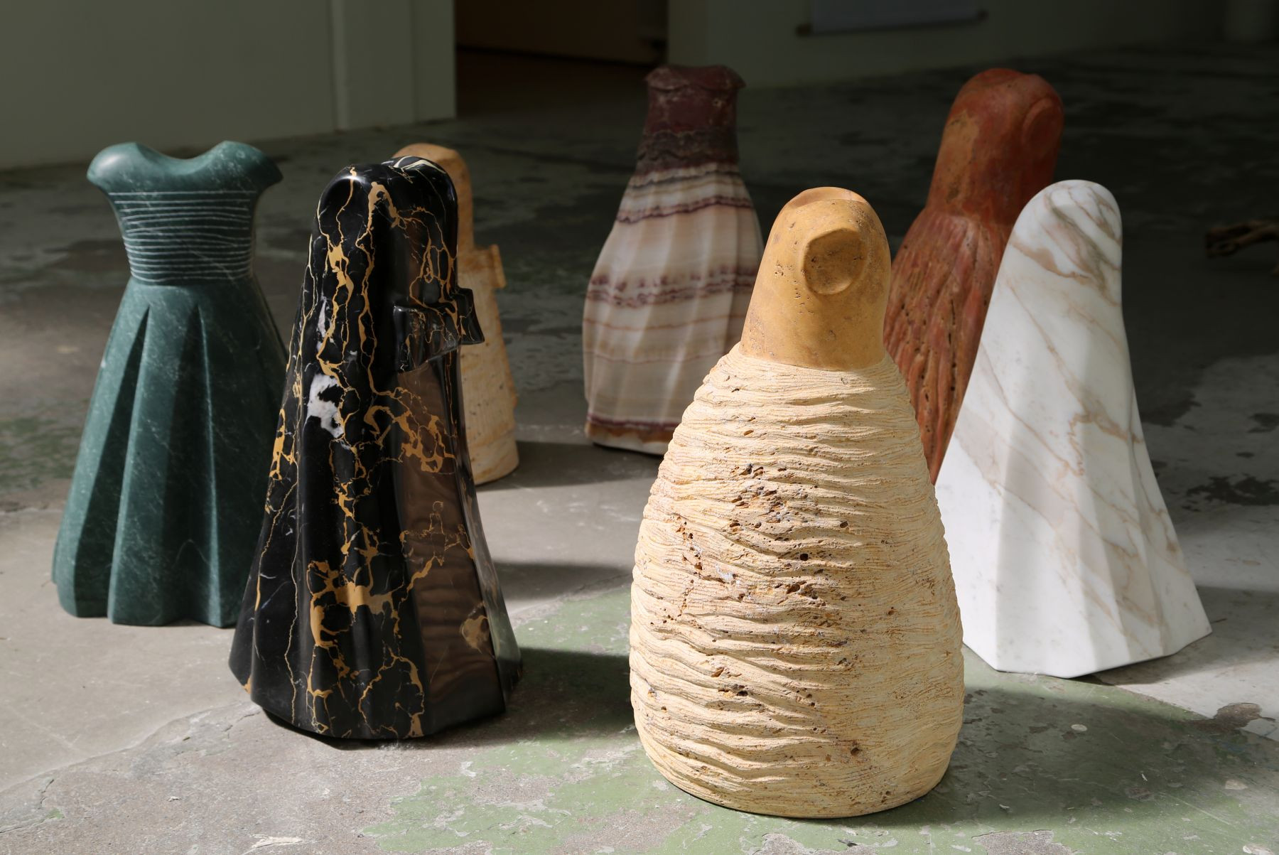 a collection of small marble sculptures of dresses in different colours and variations of styles