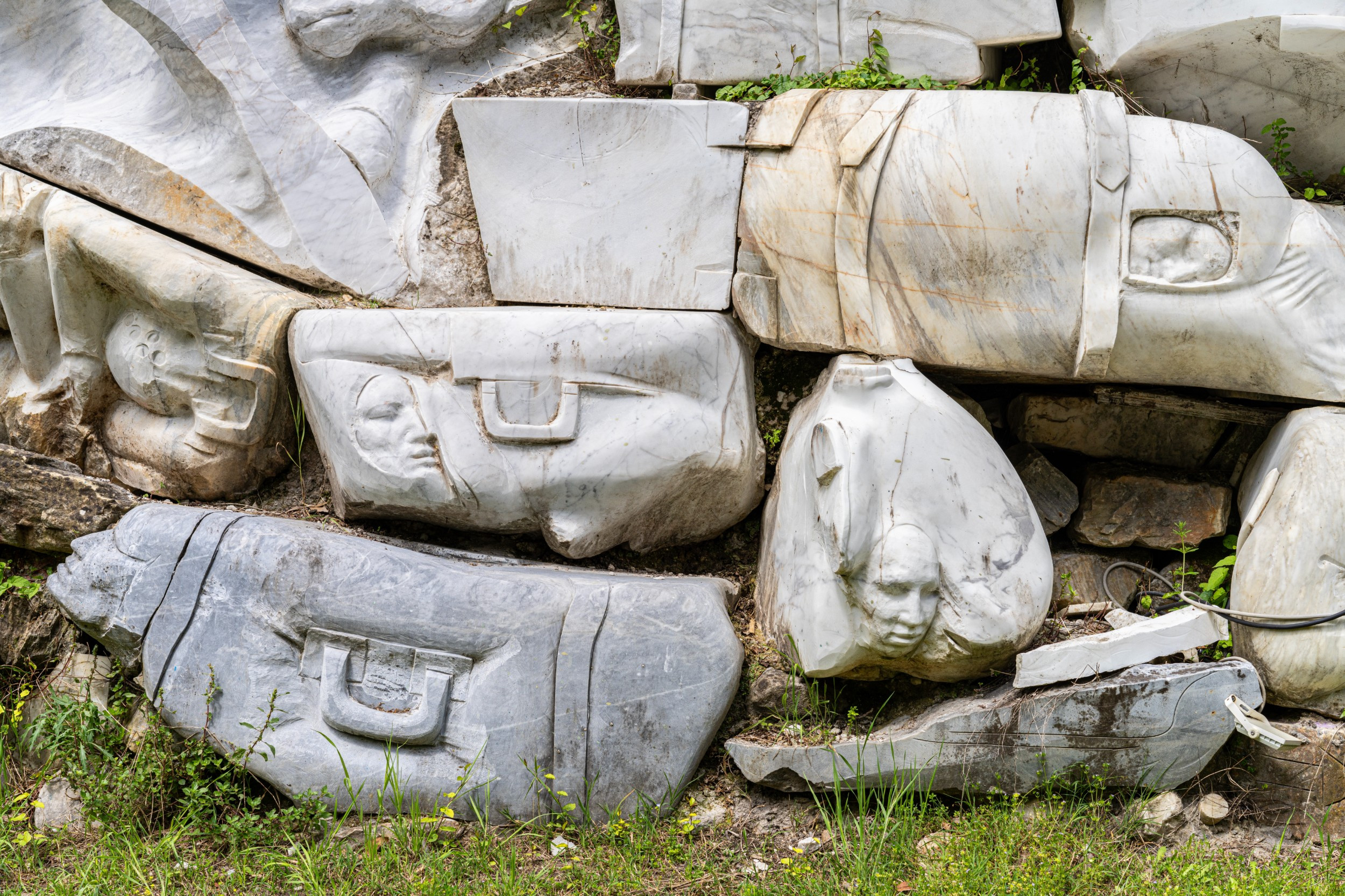 marble sculpture wall of luggage with faces