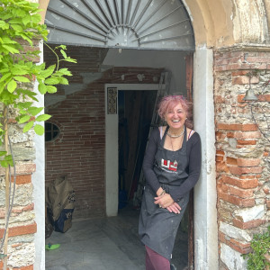 Smiling women with pink hair stood in the door way to her art studio.