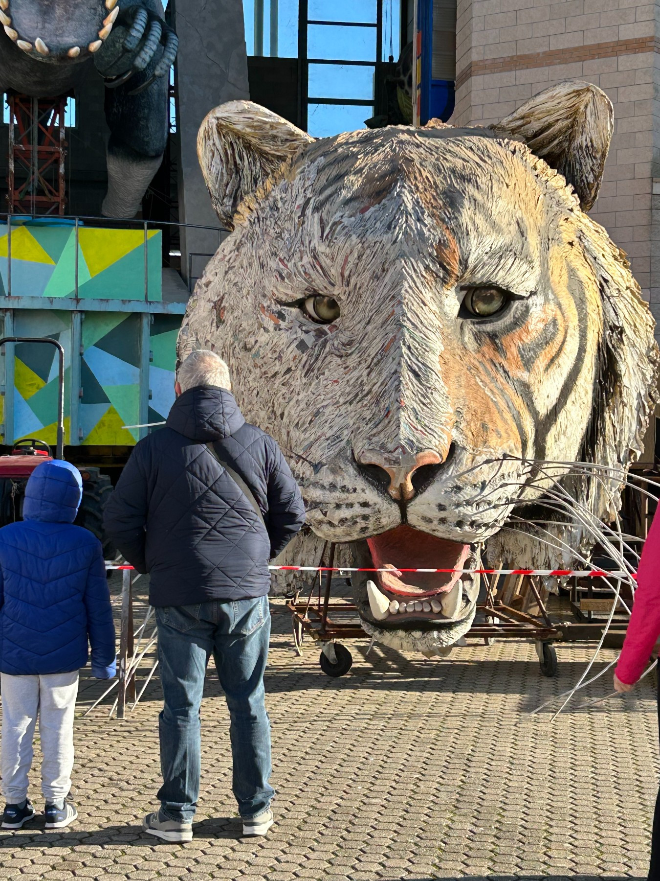 large papier-mâché lion's head with two onlookers
