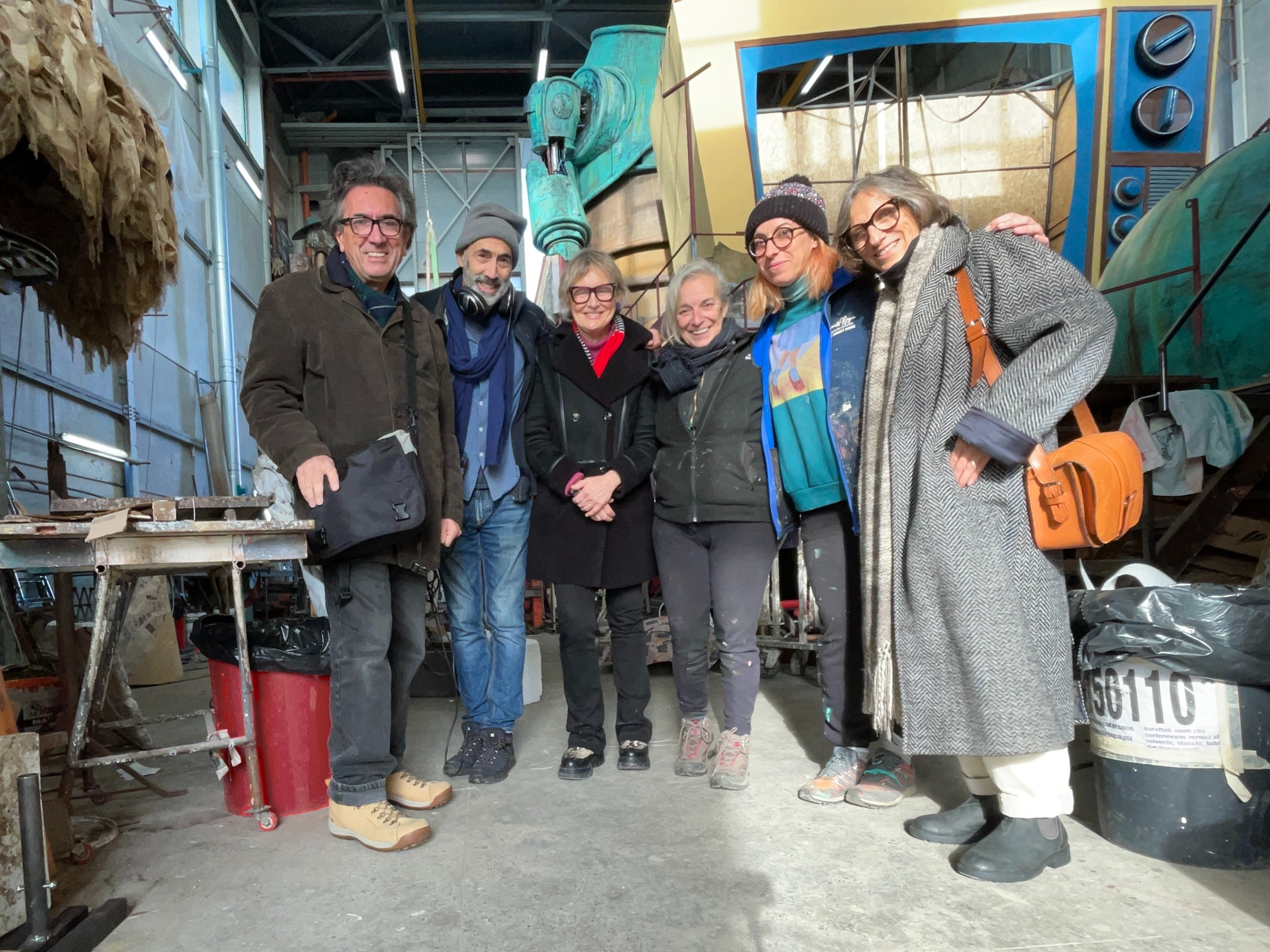 six adults in a workshop smiling and looking into the camera