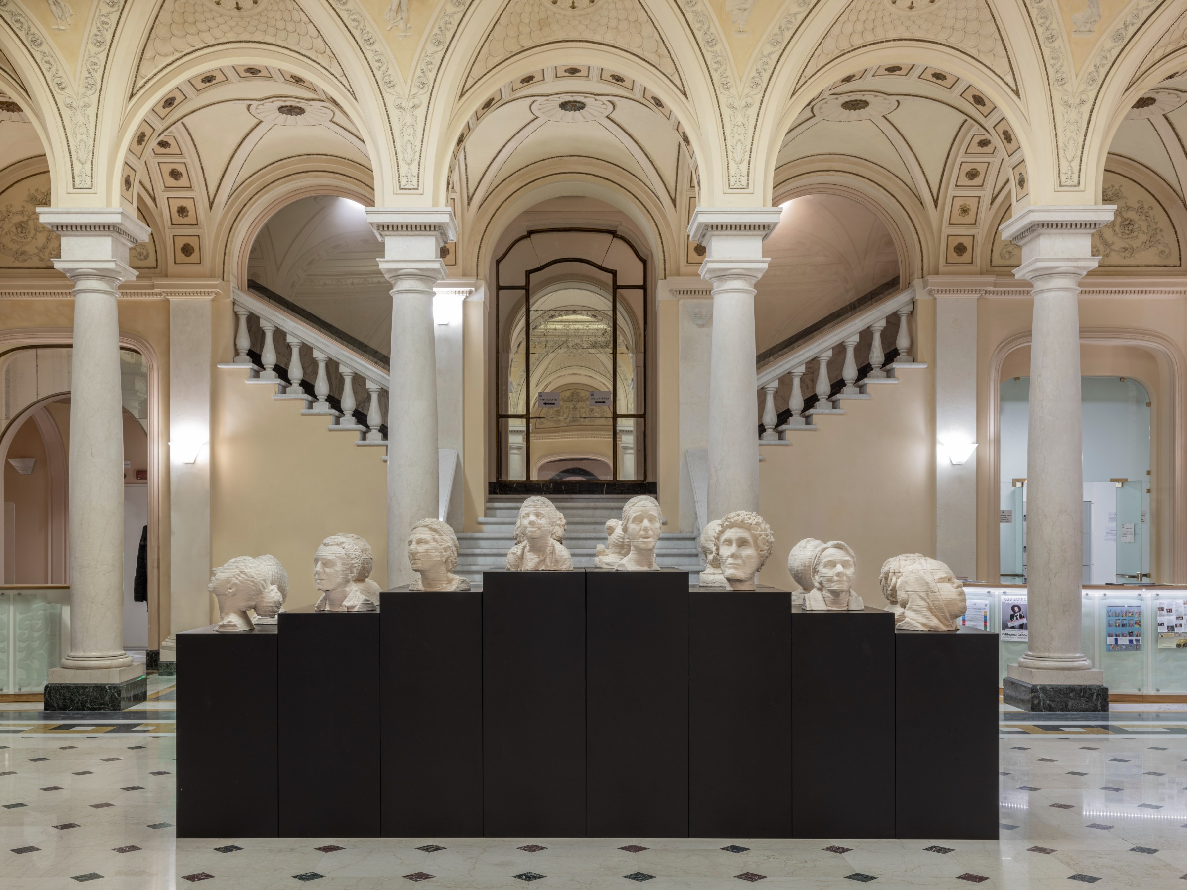a selection of white sculpted heads on plinths in a grand foyer
