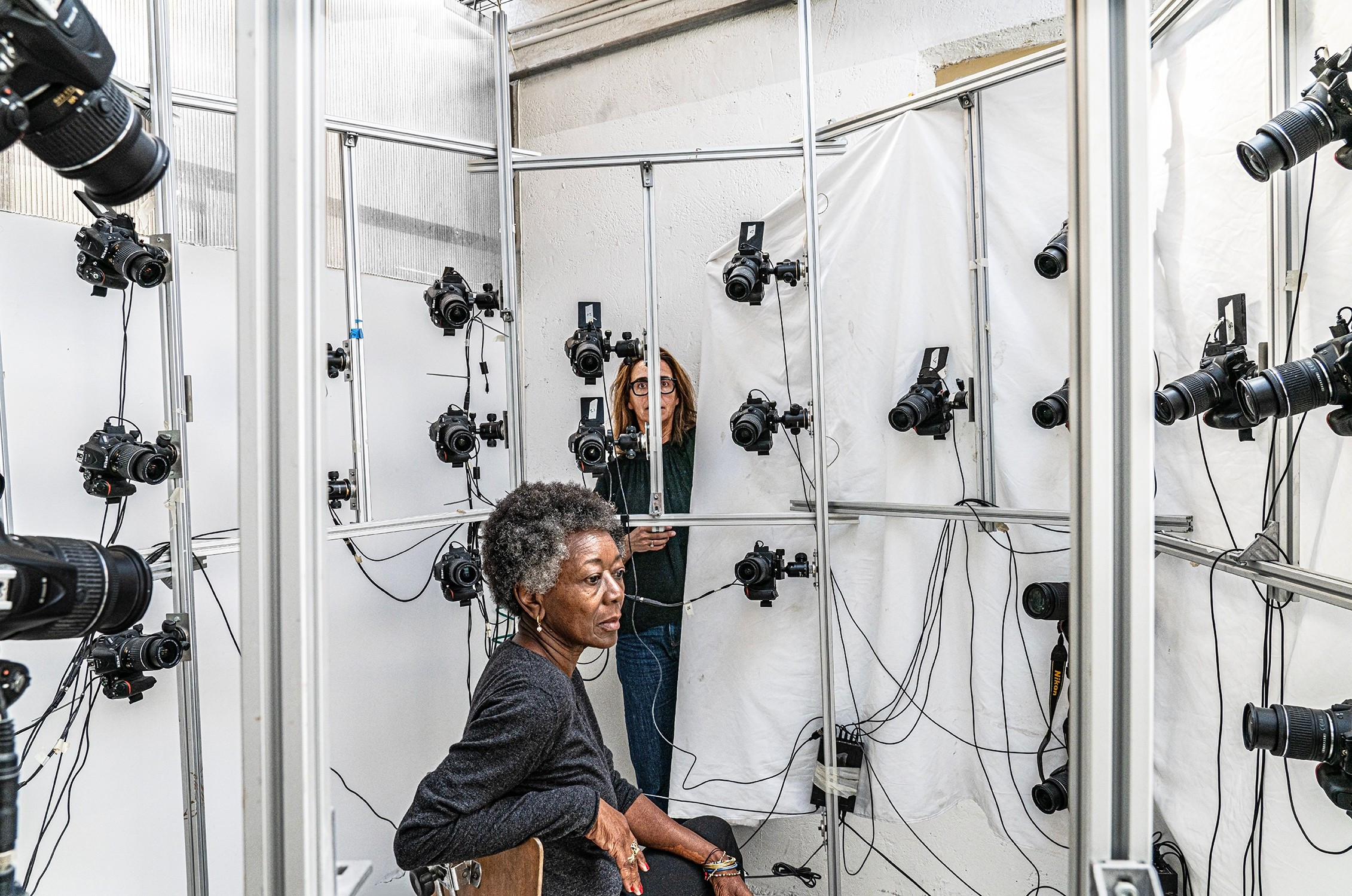 woman sitting in chair surrounded by cameras at various angles