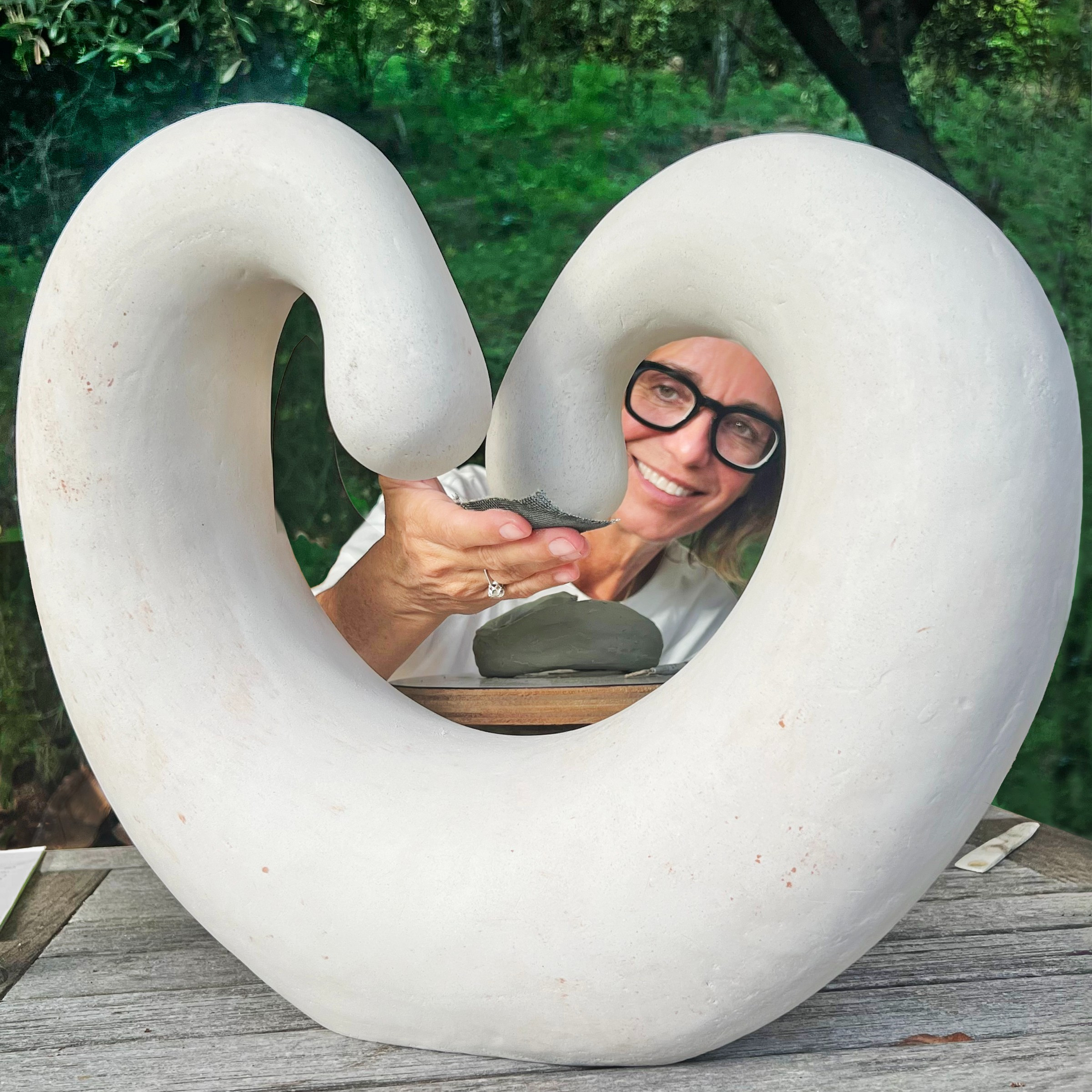 Woman sanding and peeking through a curved stone sculpture