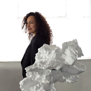 Female artist standing behind a abstract white marble sculpture