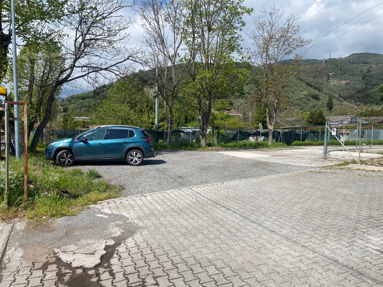 Blue car parked in an empty car park surrounded by green hills and trees