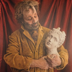 Portrait of a dusty man looking at the stone female bust he is holding