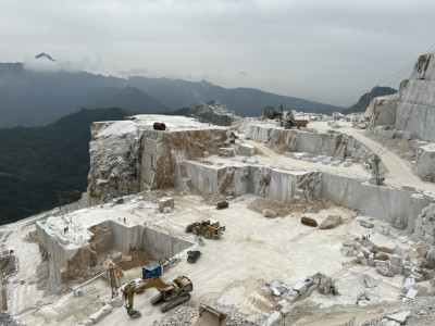 cranes and workers on a marble quarry surrounded by mountains