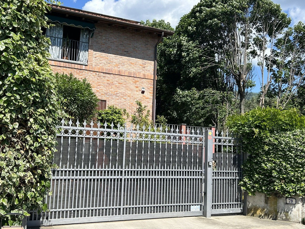Metal gates leading to red brick building and trees
