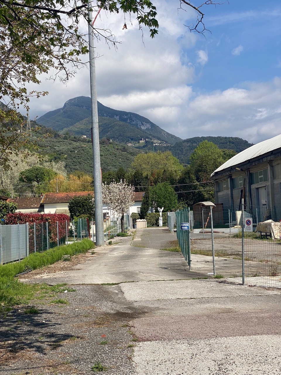 Concrete foot path leading to buildings with a backdrop of hills and mountains