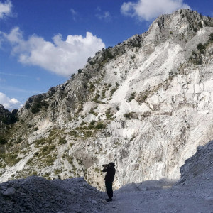 photographer in a white stone quarry with a blue ski overhead