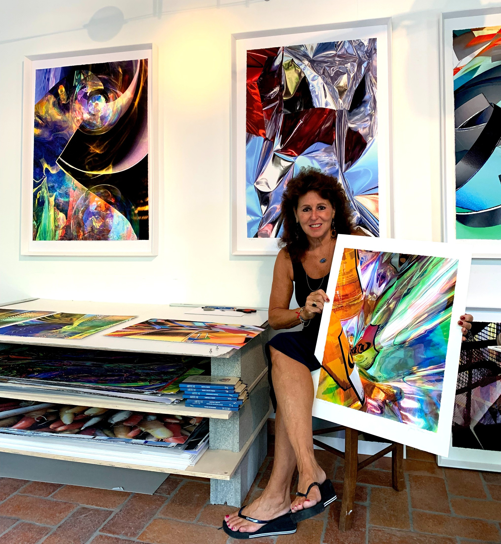 seated woman holding colourful artwork