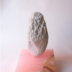 white marble sculpture with dimples on a plinth.