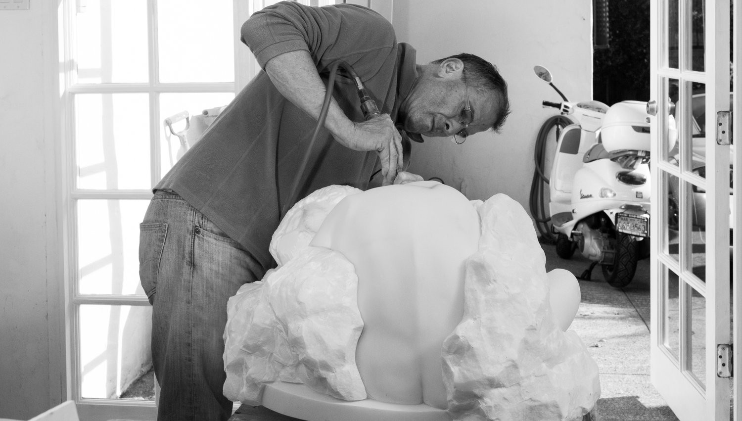 black and white photo of man sculpting white marble