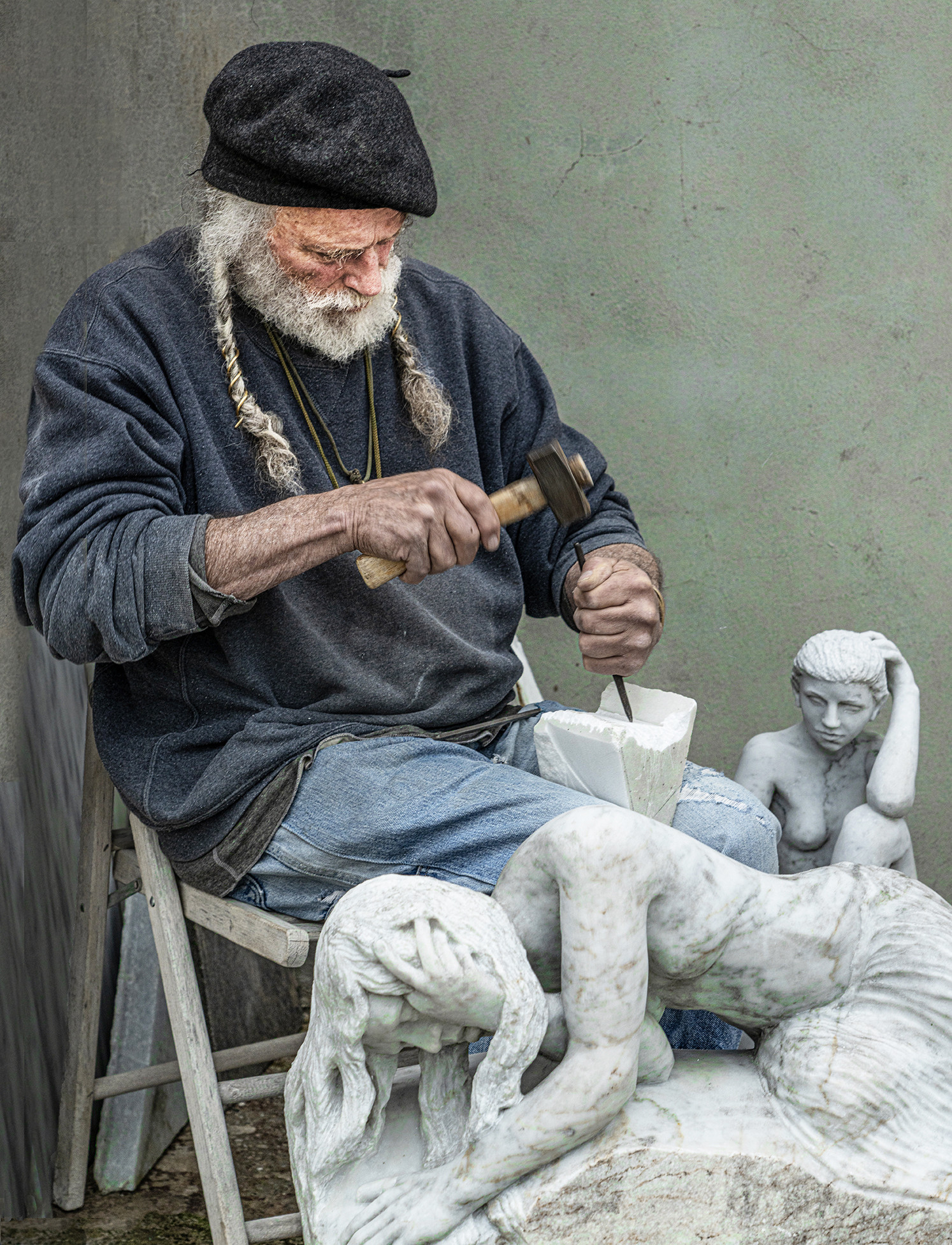 Man carving marble figures on his lap