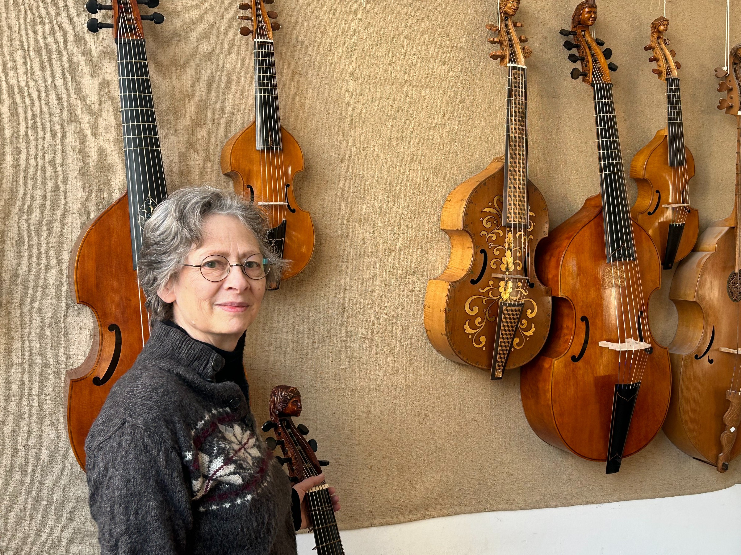 woman standing with a variety of violas and cellos