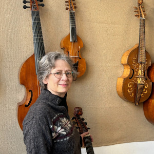 woman standing with a variety of violas and cellos