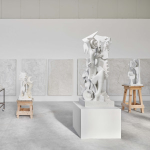 Inside a marble studio with with abstract sculptures on plinths.