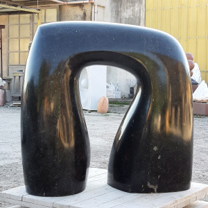 Black marble sculpture on wooden plinth outside an art studio
