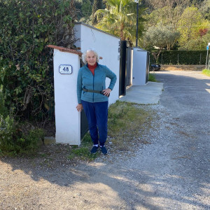 Maria Gamundi standing outside her marble studio entrance with a backdrop of trees.