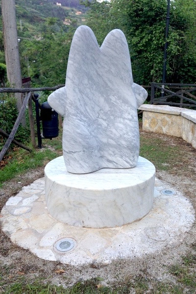 abstract marble sculpture on a circular marble plinth in a park