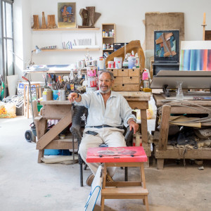 older man in art studio sitting and pointing