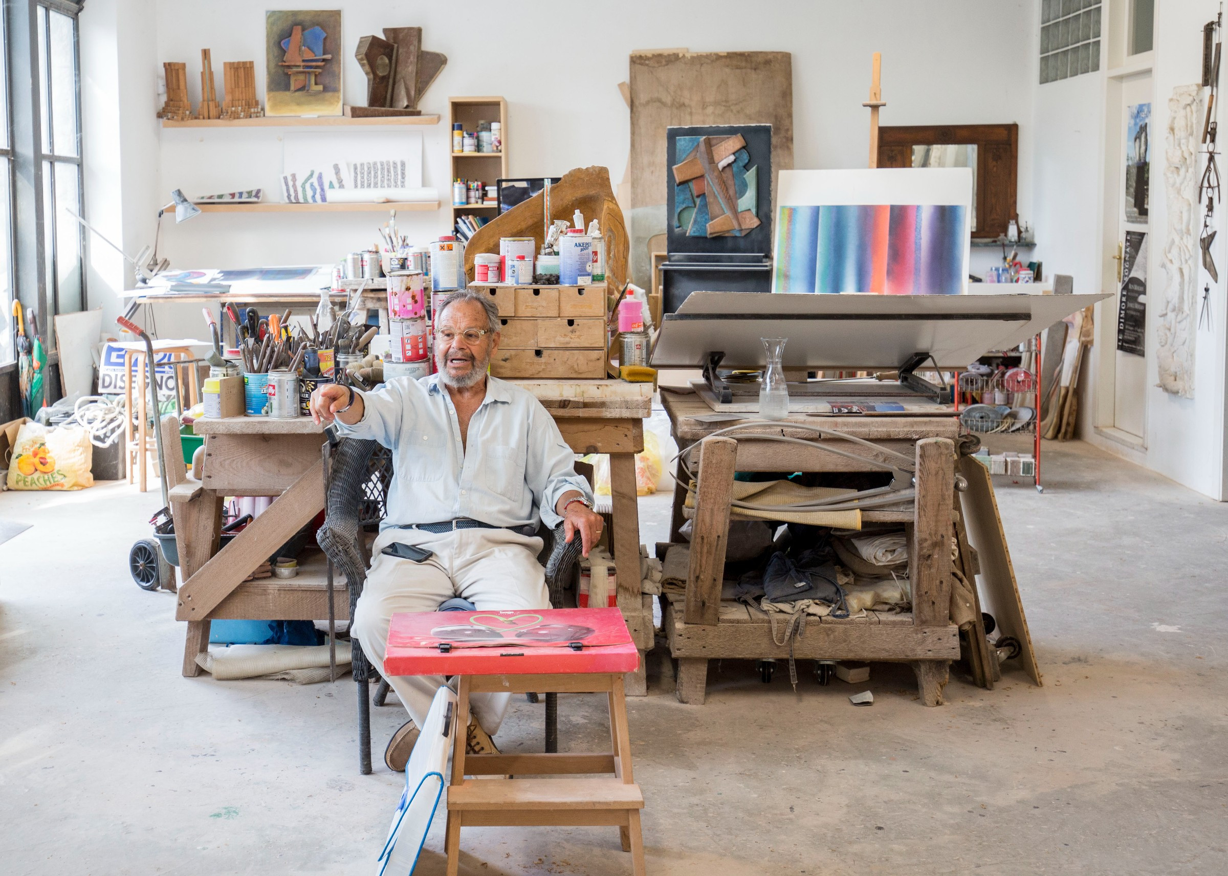 older man in art studio sitting and pointing