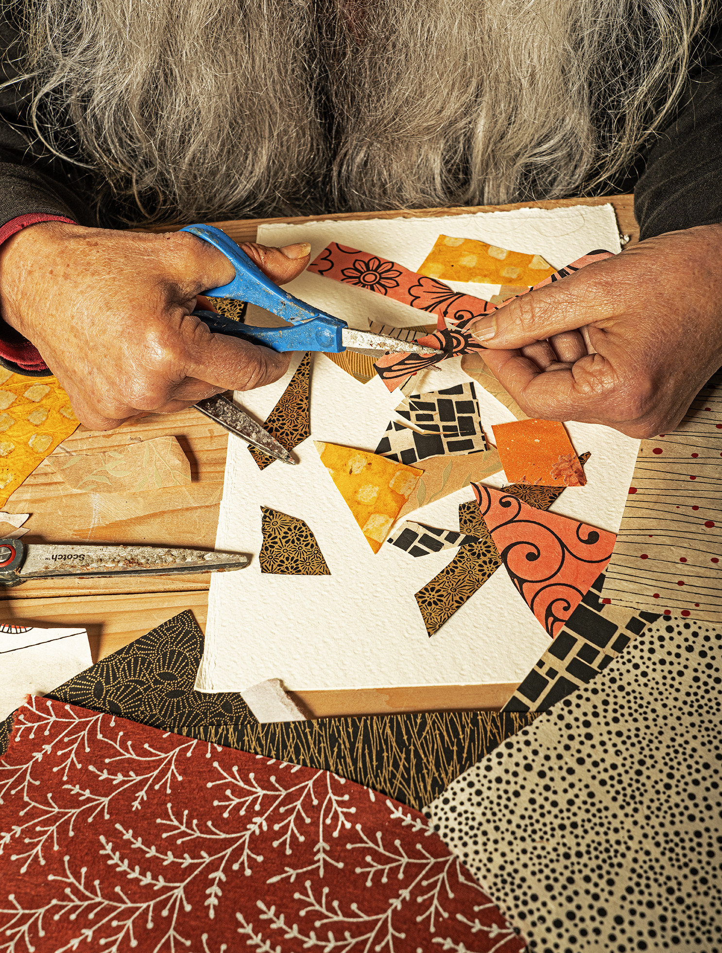 collage artist using scissors on colourful patterned paper
