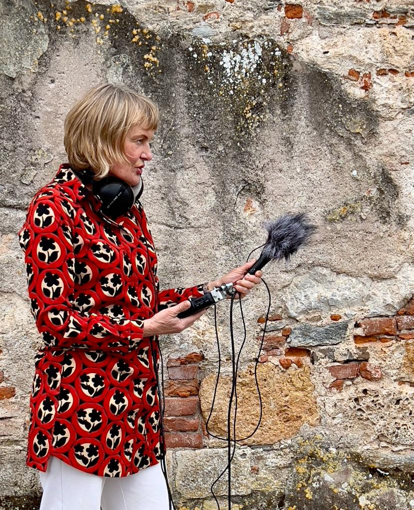 woman recording audio with a furry microphone and headphones