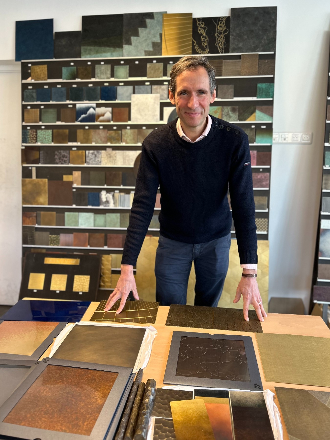 smiling man standing with a selection of sheet metal samples