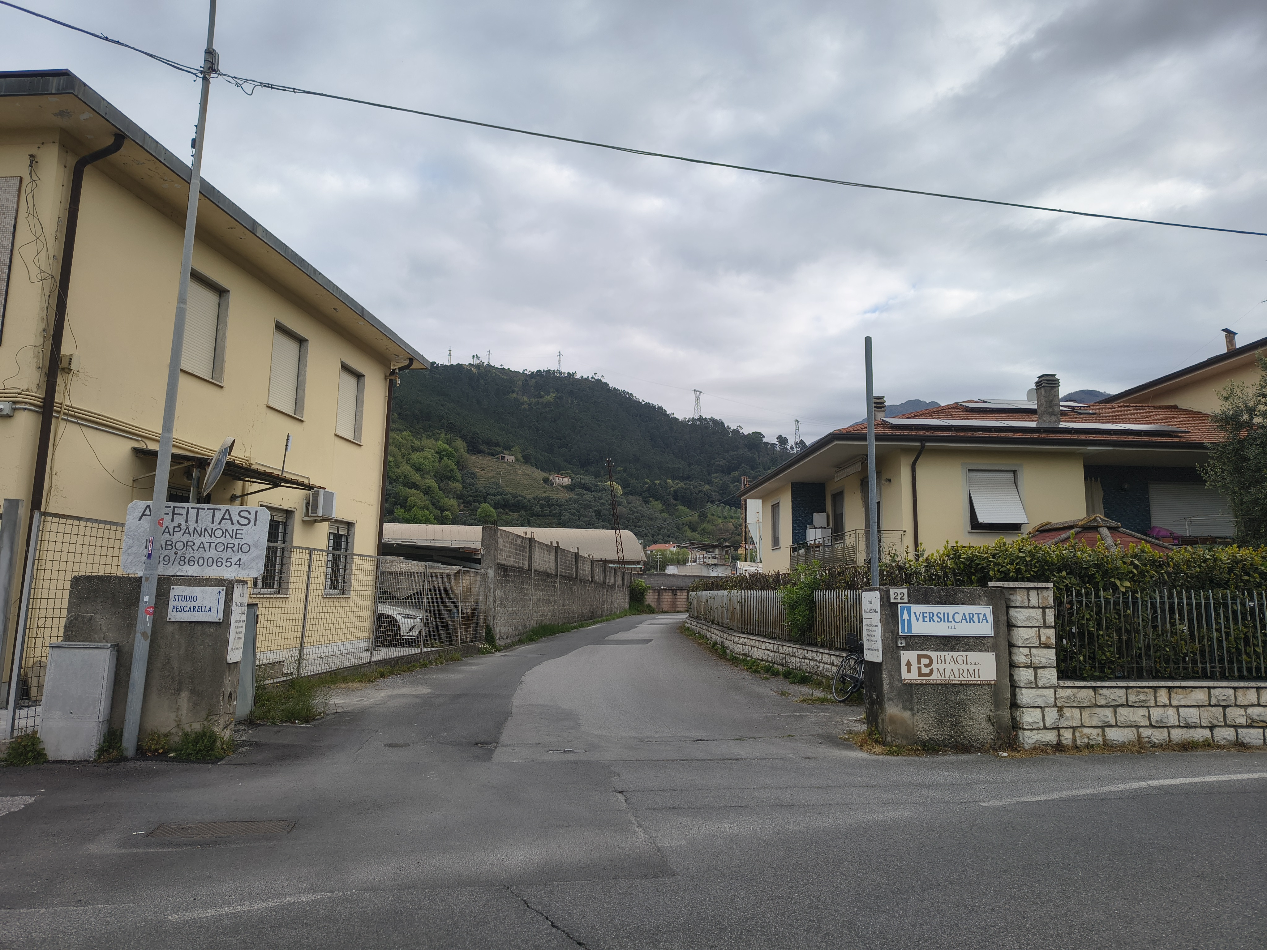 Yellow buildings and a concrete road leading to a backdrop of green hills