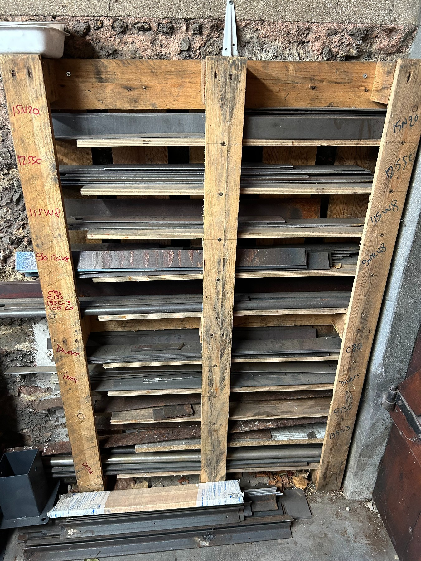 wooden rack made from a pallet holding metal bar stock